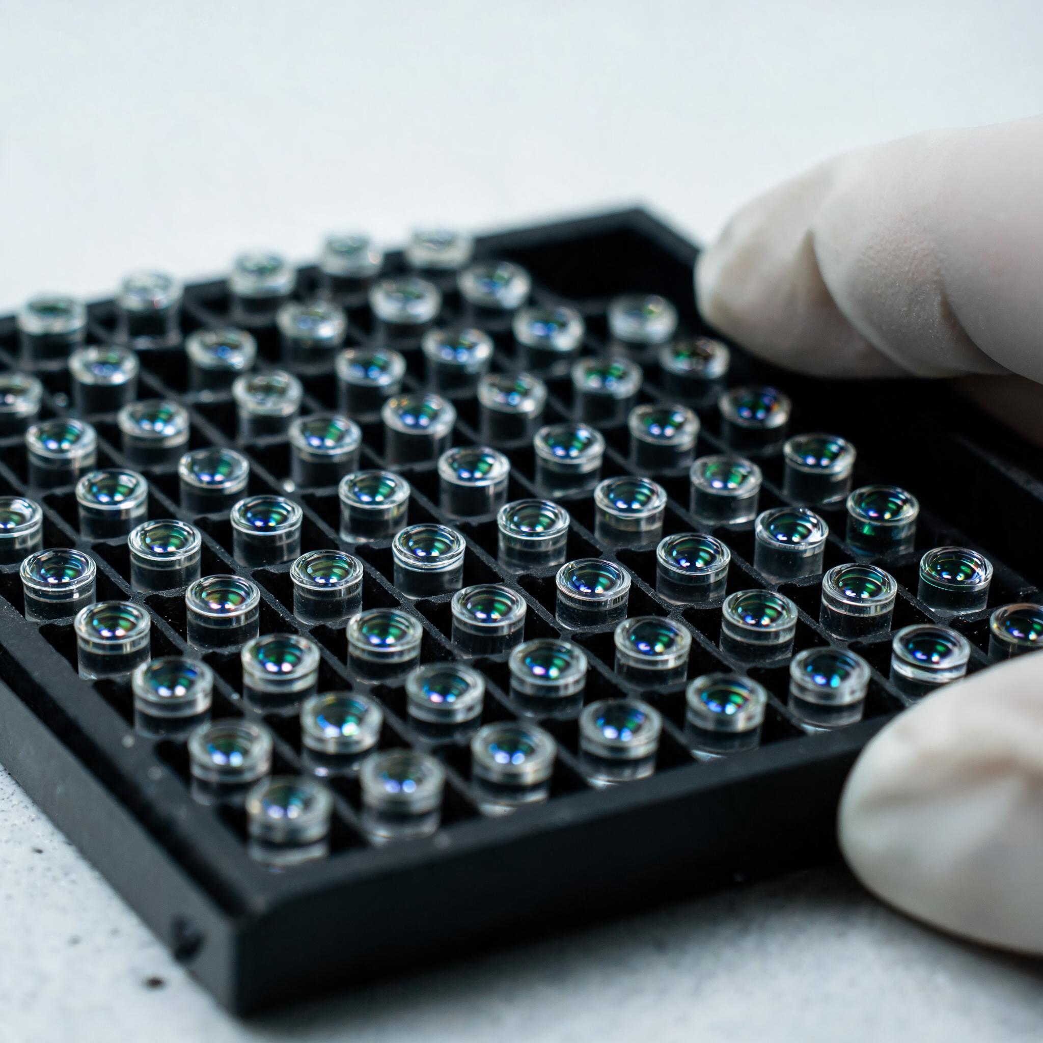 Массив миниатюрных цилиндрических стеклянных коллиматоров в чёрном держателе с зелёно-синим блеском просветления